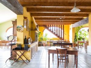 Sala degustazione di Poderi Borselli con soffitto a travi, tavoli in legno e pareti gialle